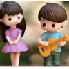 Two musical couple figurines, a girl and a boy, in purple and blue, for cake or decor.