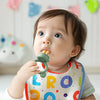 A baby is using a silicone fruit feeder set to feed food.