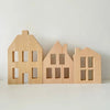 Three wooden building blocks shaped like houses in light natural wood color