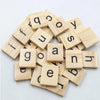 A collection of wooden alphabet letter tiles scattered on a white surface.