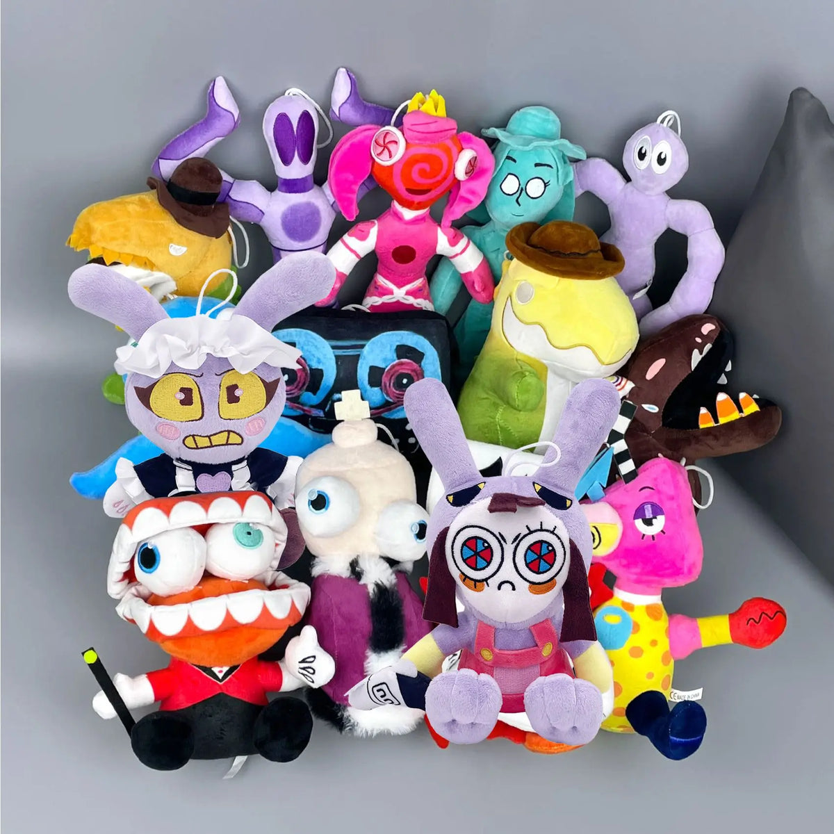 A collection of colorful plush toys featuring characters from The Amazing Digital Circus