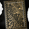 A rectangular frame displaying a dark background with intricate gold foil celestial and botanical patterns.