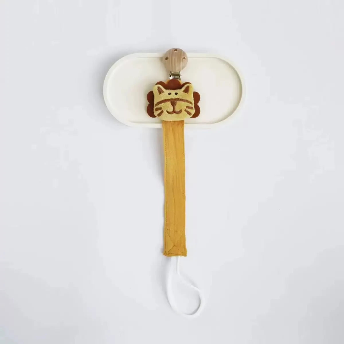 A wooden elephant pacifier holder with a clip mounted on a white tray.