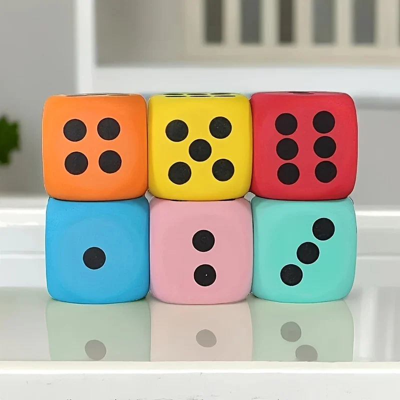 A set of five brightly colored jumbo soft foam dice in orange, yellow, red, blue, and pink resting on a white surface.