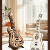 A detailed wooden miniature guitar model kit with intricate carvings displayed on a white marble surface.