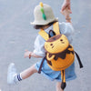 Un enfant portant un chapeau clair et un vêtement bleu avec un sac à dos orange et une sangle de sécurité.