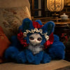 A fluffy blue fox plush collectible with white accents sitting on a wooden surface next to a lit lamp.