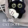 A black cat doll plush with yellow eyes and a white paw print charm attached to a light gray fabric item.
