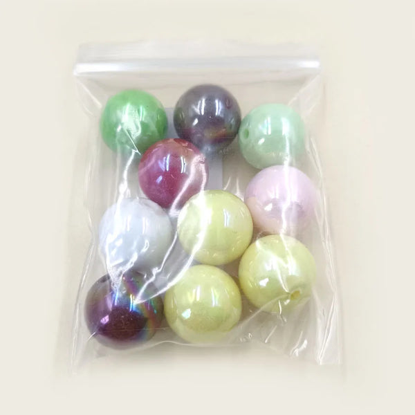 A clear plastic bag contains various round acrylic magic color beads for jewelry making.