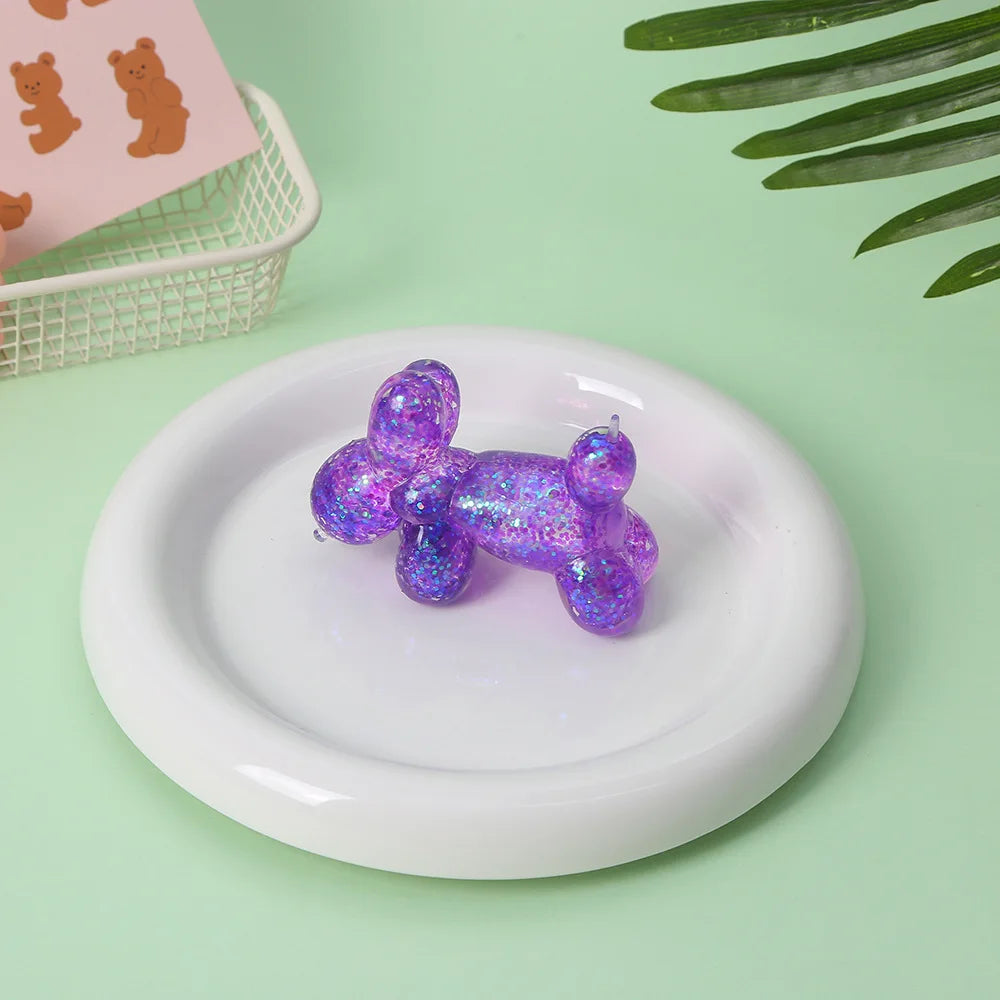 A purple translucent stress ball squishy toy resting on a white plate with a pink background.