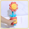 A hand is holding a colorful sunflower bath shower sprinkler toy for kids with pink and yellow flower shapes.