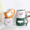 Three ceramic mugs featuring pink heart and bow decals in orange, white, and green colors.