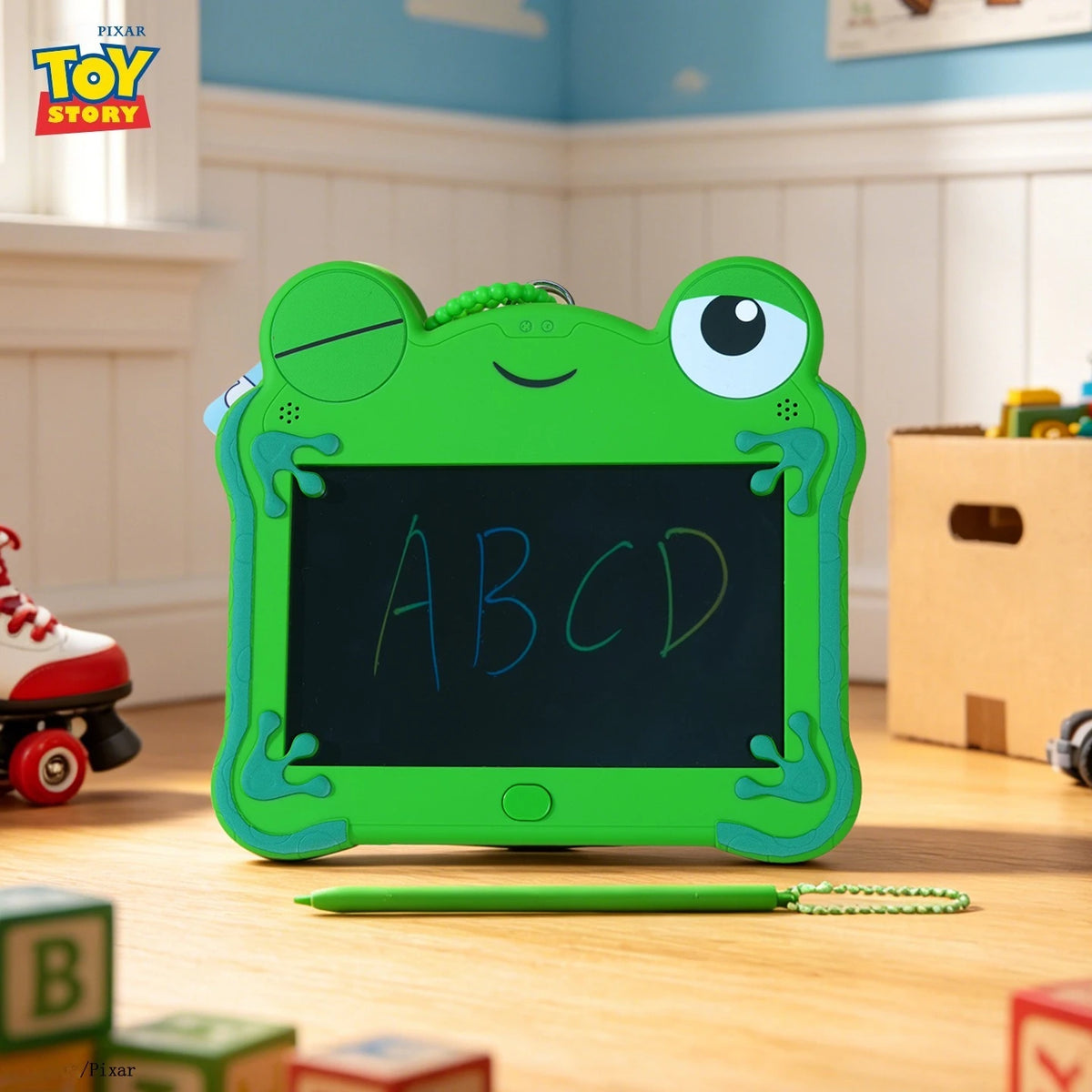 A bright green frog-shaped LCD drawing tablet with a keypad and stylus rests on a wooden surface.