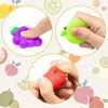 Three squishy toys shaped like a purple, green, and red fruit or vegetable are shown being squeezed by hands.