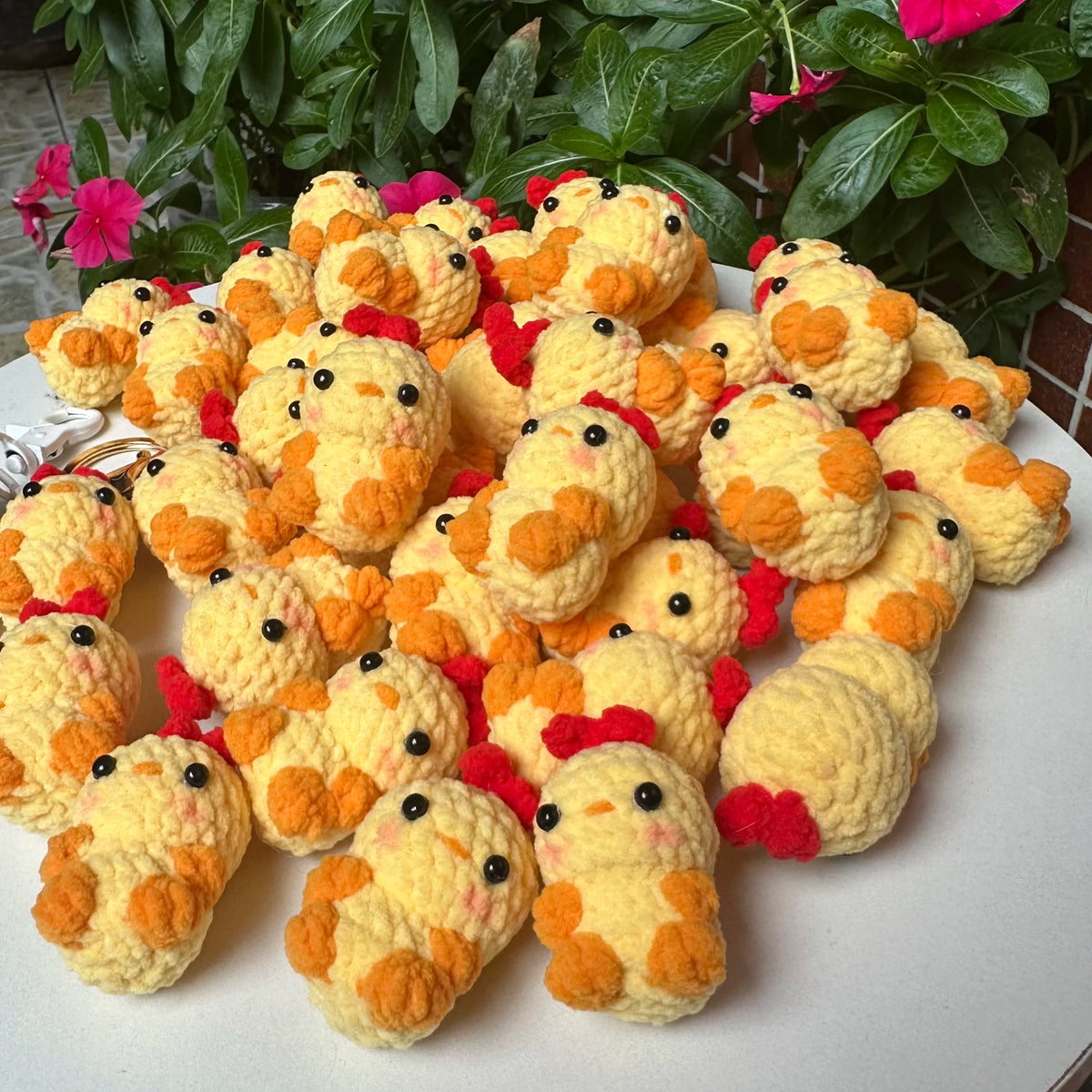 A pile of handmade crochet yellow and orange chick animals used as keychains or knitted pendants.