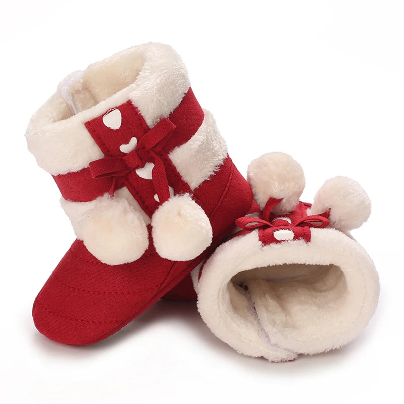 A pair of red baby winter boots with white faux fur trim and a red bow detail.