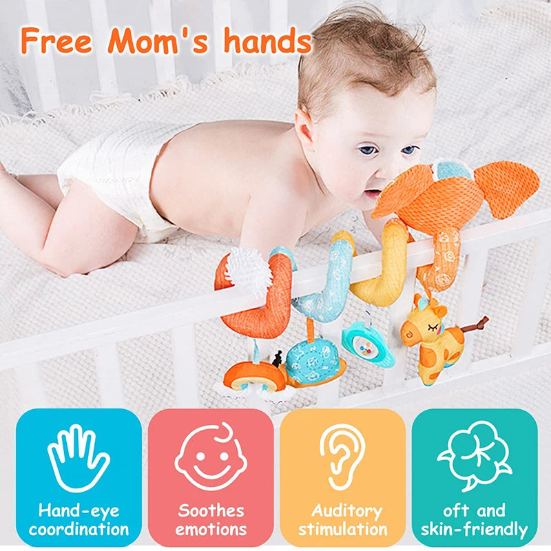 A baby is interacting with various orange and yellow sensory toys, including a spiral elephant toy, in a crib setting.