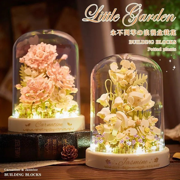 A glass terrarium filled with white jasmine flowers and green moss, displayed next to a wooden book.