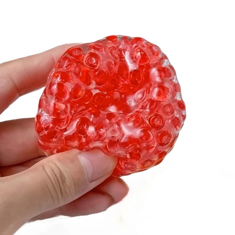 A hand holds a translucent red mochi squeeze toy, which is a soft fidget ball for stress relief.
