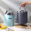 A hand is holding a purple stackable bento lunch box for kids with a lid, next to a light blue one.