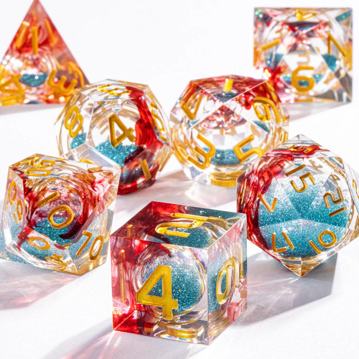 A set of handmade liquid core polyhedral dice in various colors and galaxy finishes scattered on a white surface.