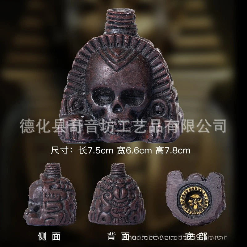 A dark bronze Aztec death whistle skull product shown from the front and side views.