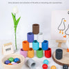 Assorted wooden ball and cup toys in various colors arranged on a white surface.