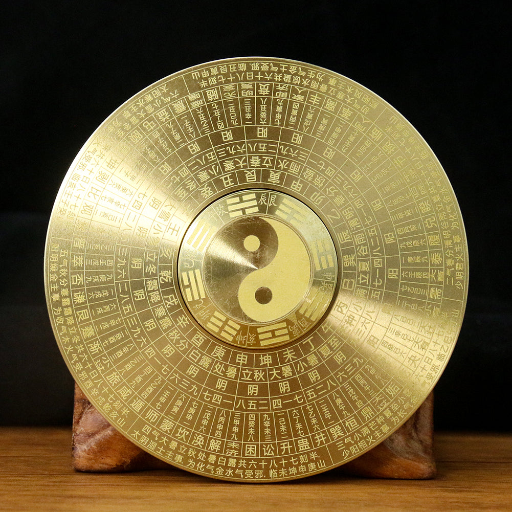 A round brass compass featuring a prominent yin and yang symbol engraved on its surface.