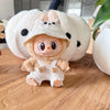 A Labubu doll wearing a beige hoodie and headphones, sitting in front of a large white fluffy object.