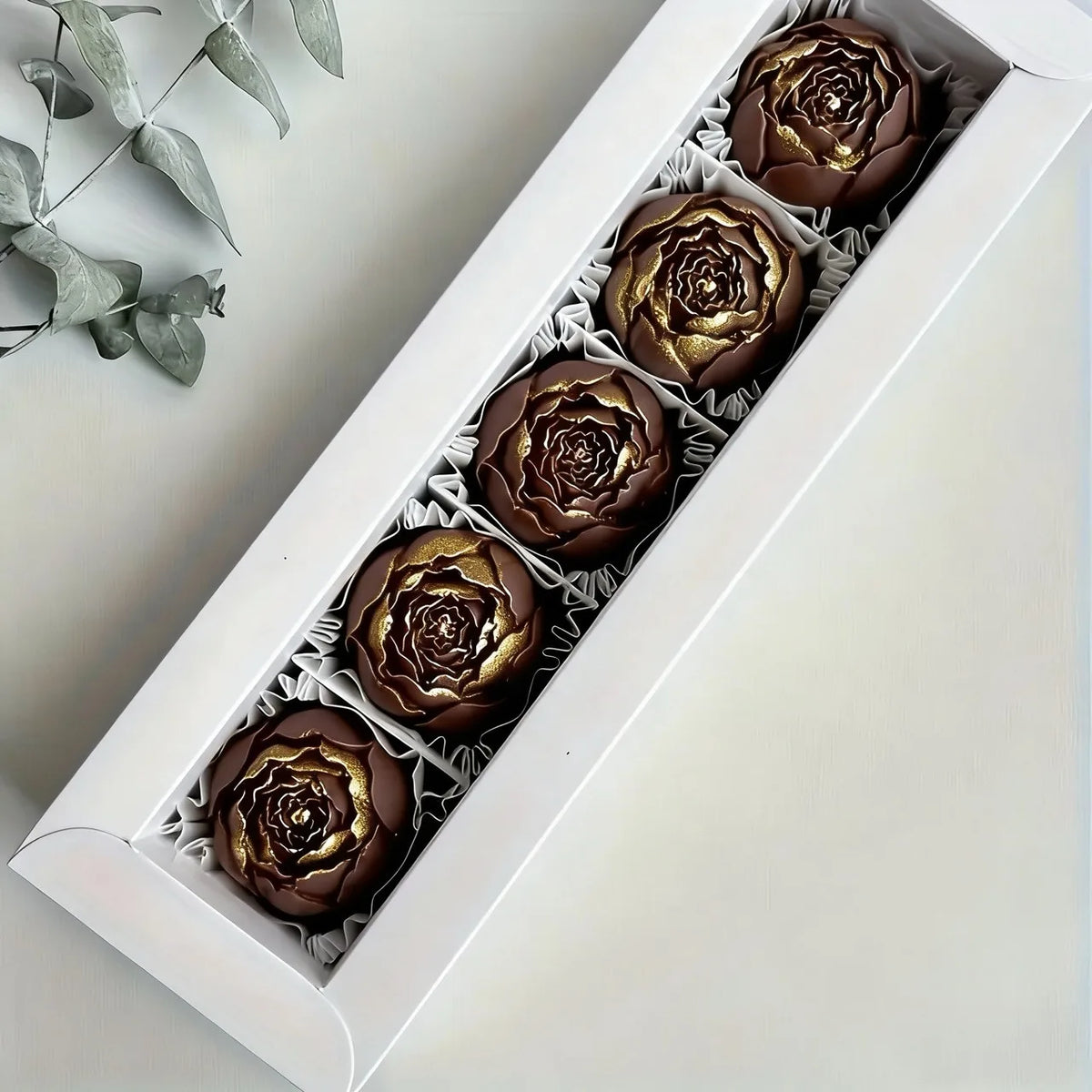 A white box filled with six dark chocolate rosette leaves for cake and chocolate decorating.