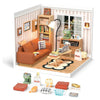 A miniature house kit featuring a brown sofa, wooden furniture, and various household items displayed in a striped room setti