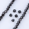 A close-up view of black faceted glass beads arranged in strands and loose pieces for jewelry making
