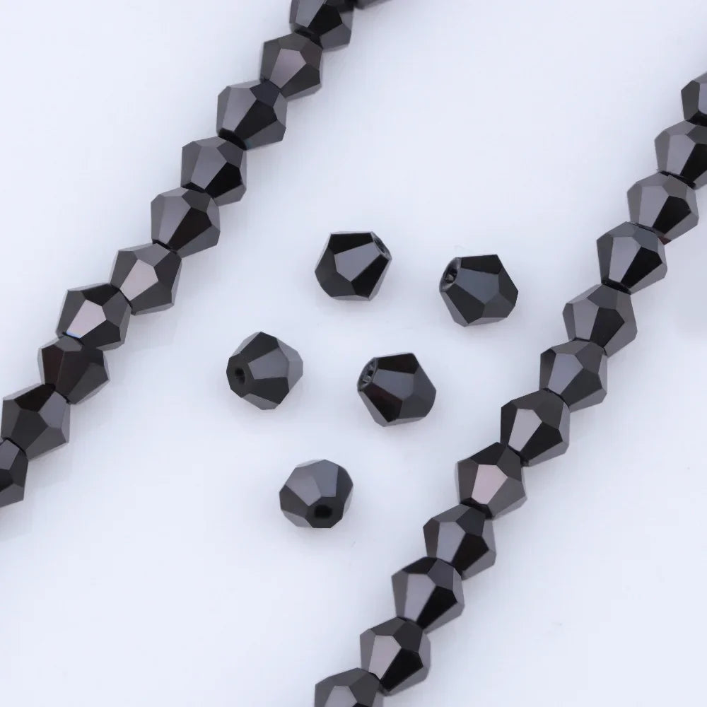 A close-up view of black faceted glass beads arranged in strands and loose pieces for jewelry making