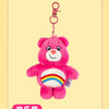 A pink Care Bears plush toy keychain with a rainbow belly, hanging from a metal ring.