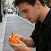 A man holds a realistic orange stress ball, demonstrating the slow rising squeeze toy.