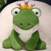 A cute green frog prince plush toy with a gold crown sitting on a white background.