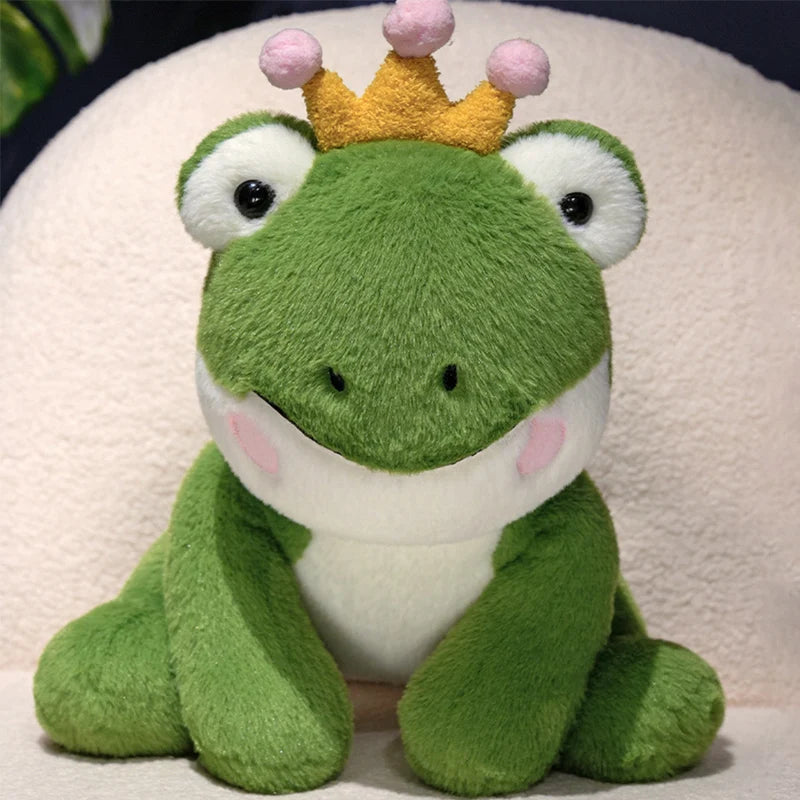 A cute green frog prince plush toy with a gold crown sitting on a white background.