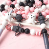 A collection of pink and black silicone craft beads arranged on a white surface.