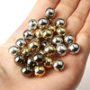 A hand holds a cluster of round spacer beads in gold and silver tones for DIY jewelry making.