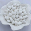 A pile of small, white, heart-shaped ceramic beads for jewelry making.
