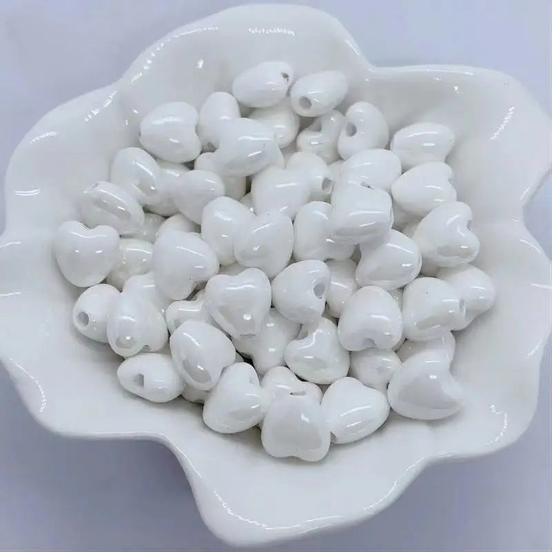A pile of small, white, heart-shaped ceramic beads for jewelry making.