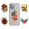 A collection of five tattoo-style cartoon stickers featuring skulls, roses, a heart, and a bird on a silver phone case.