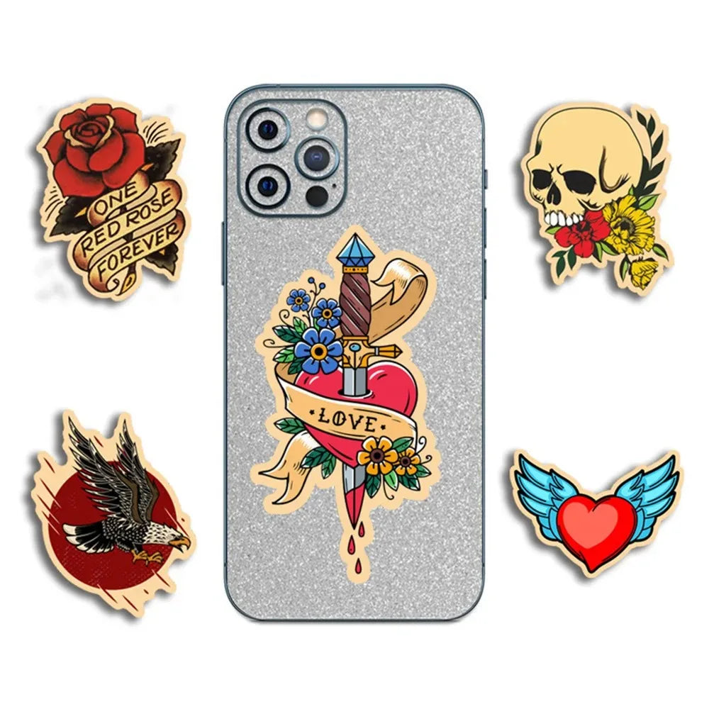 A collection of five tattoo-style cartoon stickers featuring skulls, roses, a heart, and a bird on a silver phone case.