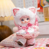 A pink and white fluffy cat plush keychain with pink accents sitting on a pink checkered cloth.