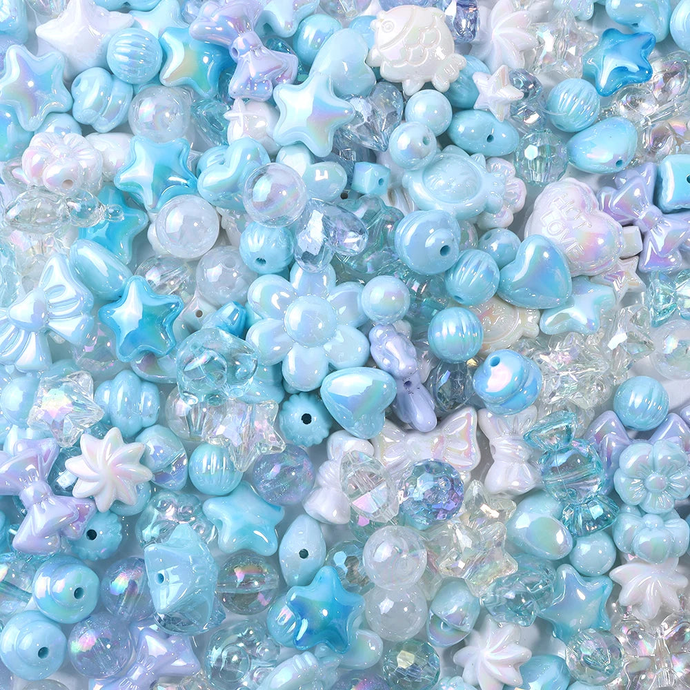 A close-up of iridescent blue and purple acrylic bow beads scattered on a white surface.