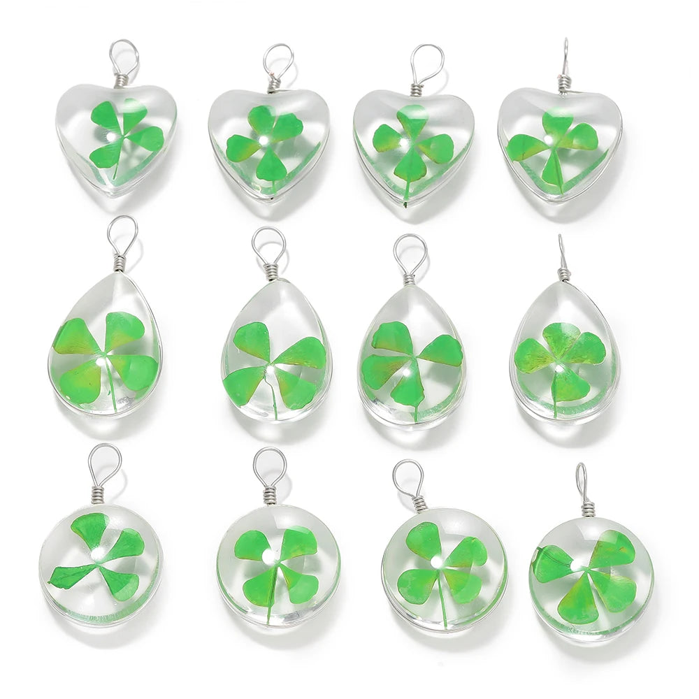 A set of twelve handmade glass four leaf clover pendants for jewelry making displayed against a white background.