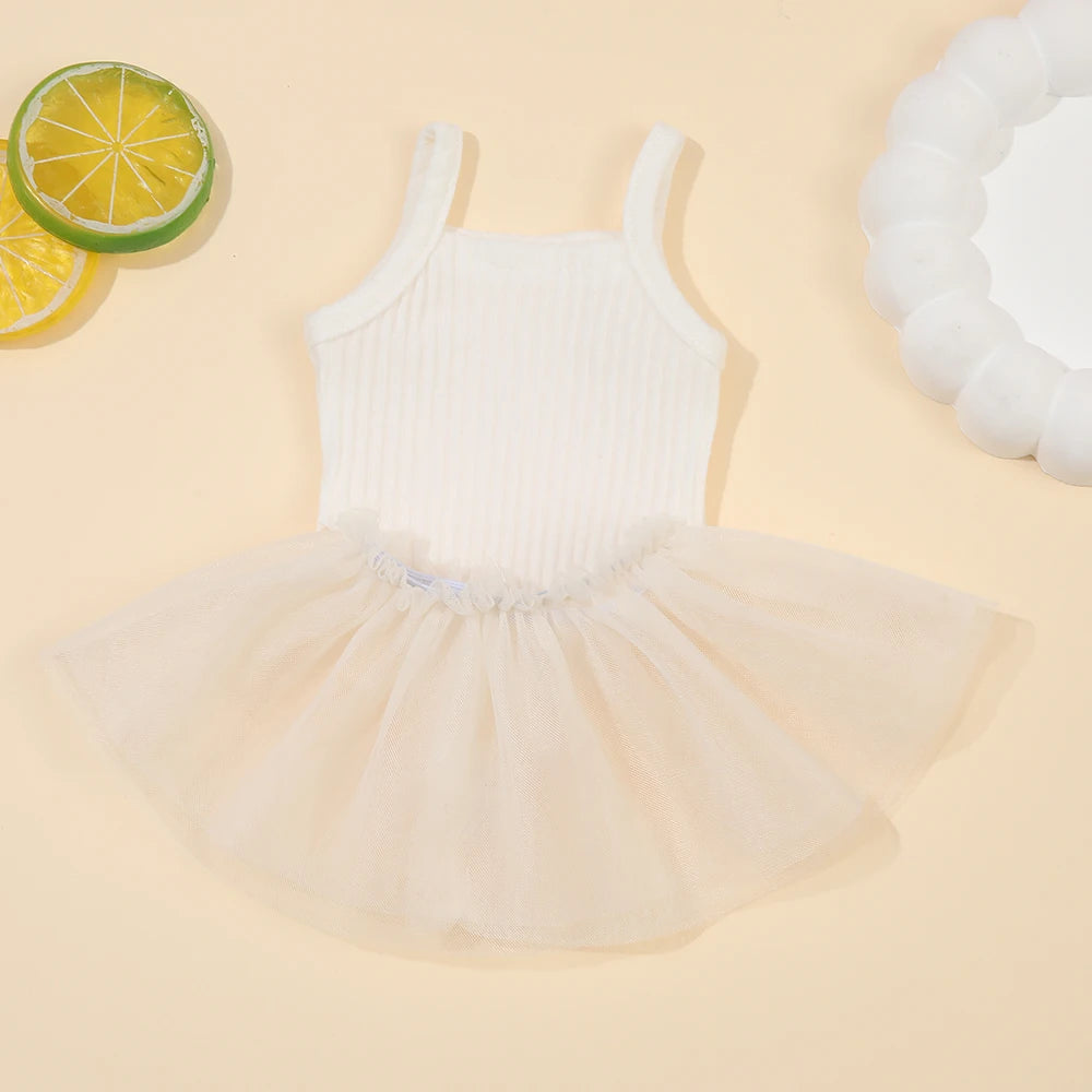 A white ribbed top and tulle skirt set for a baby doll, accompanied by a slice of lime.