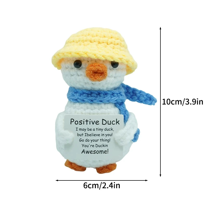 Handmade crochet duck doll with a yellow hat and blue body featuring an inspirational message