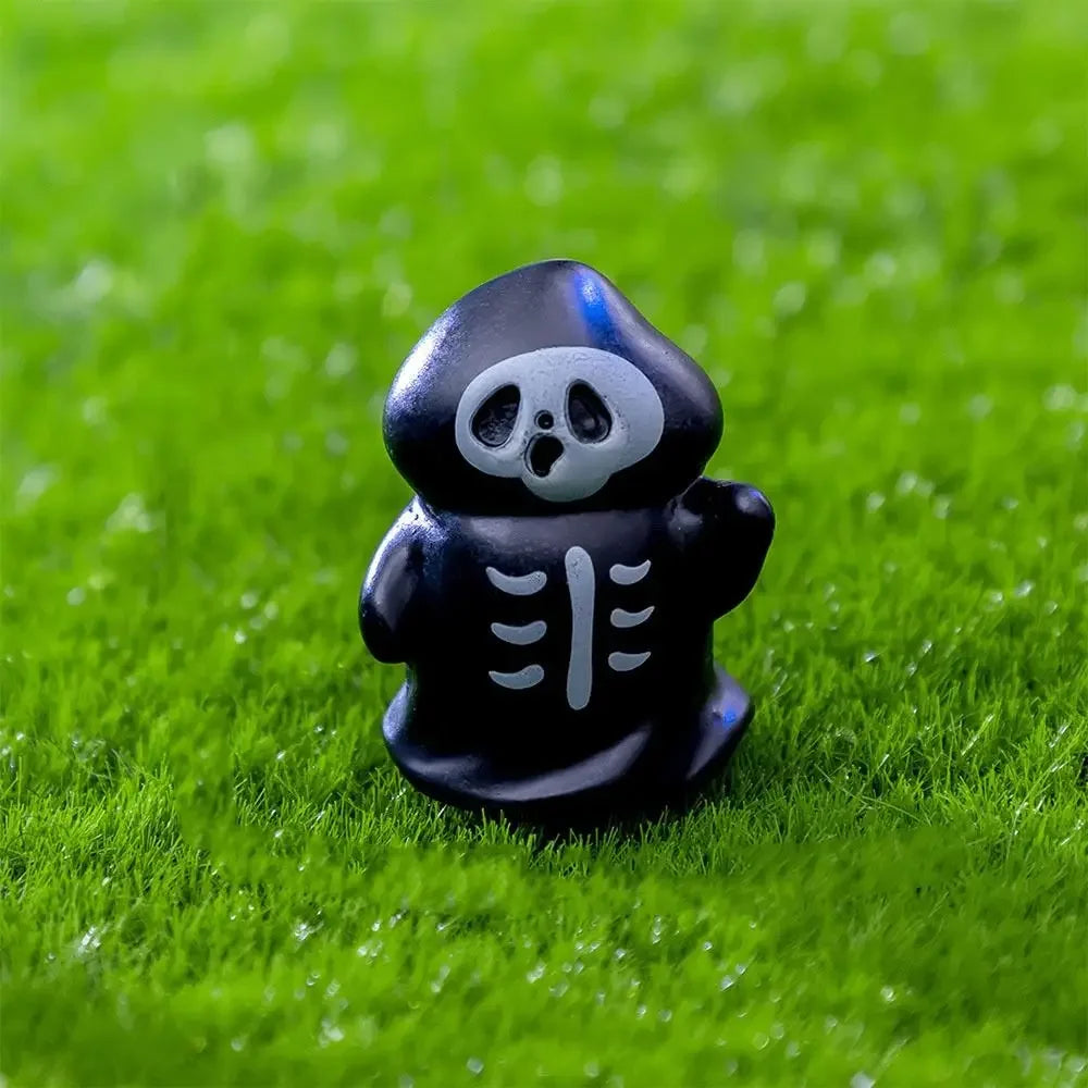 A black figurine shaped like a cartoon skull bear standing on green grass.