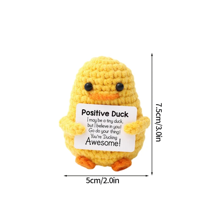 A yellow crochet duck doll with black eyes and an inspirational message tag.